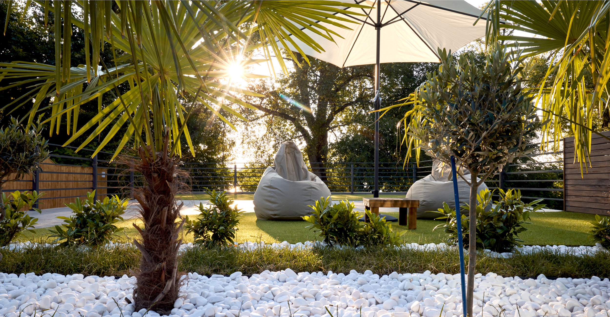 Espace extérieur aménagé avec piscine coque entourée de végétation tropicale, palmiers, et mobilier confortable pour la détente, créant une ambiance relaxante et moderne.