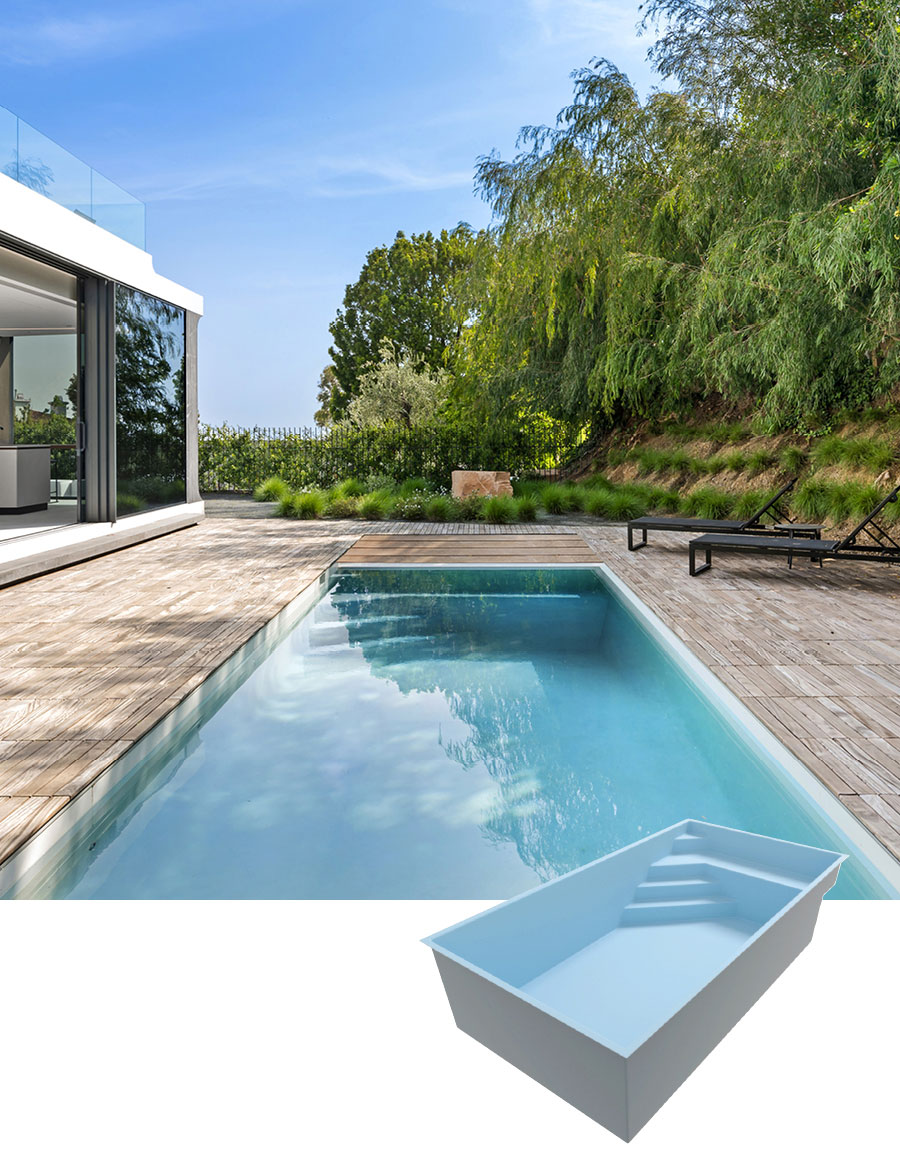 Piscine coque rectangulaire moderne dans un jardin avec terrasse en bois, entourée de plantes luxuriantes et une maison contemporaine aux grandes baies vitrées.